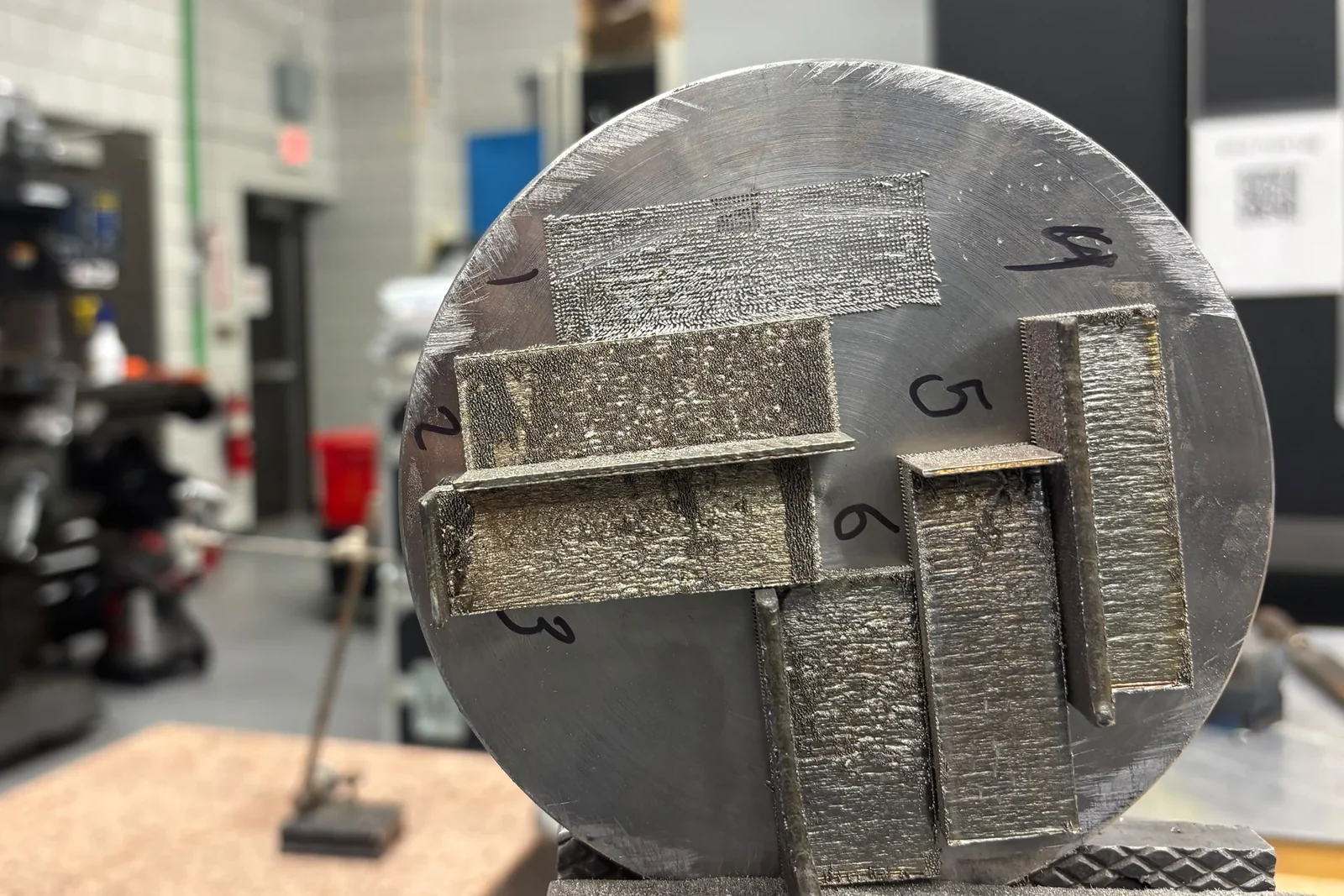 Metal specimens arranged on a circular build plate in a laboratory
